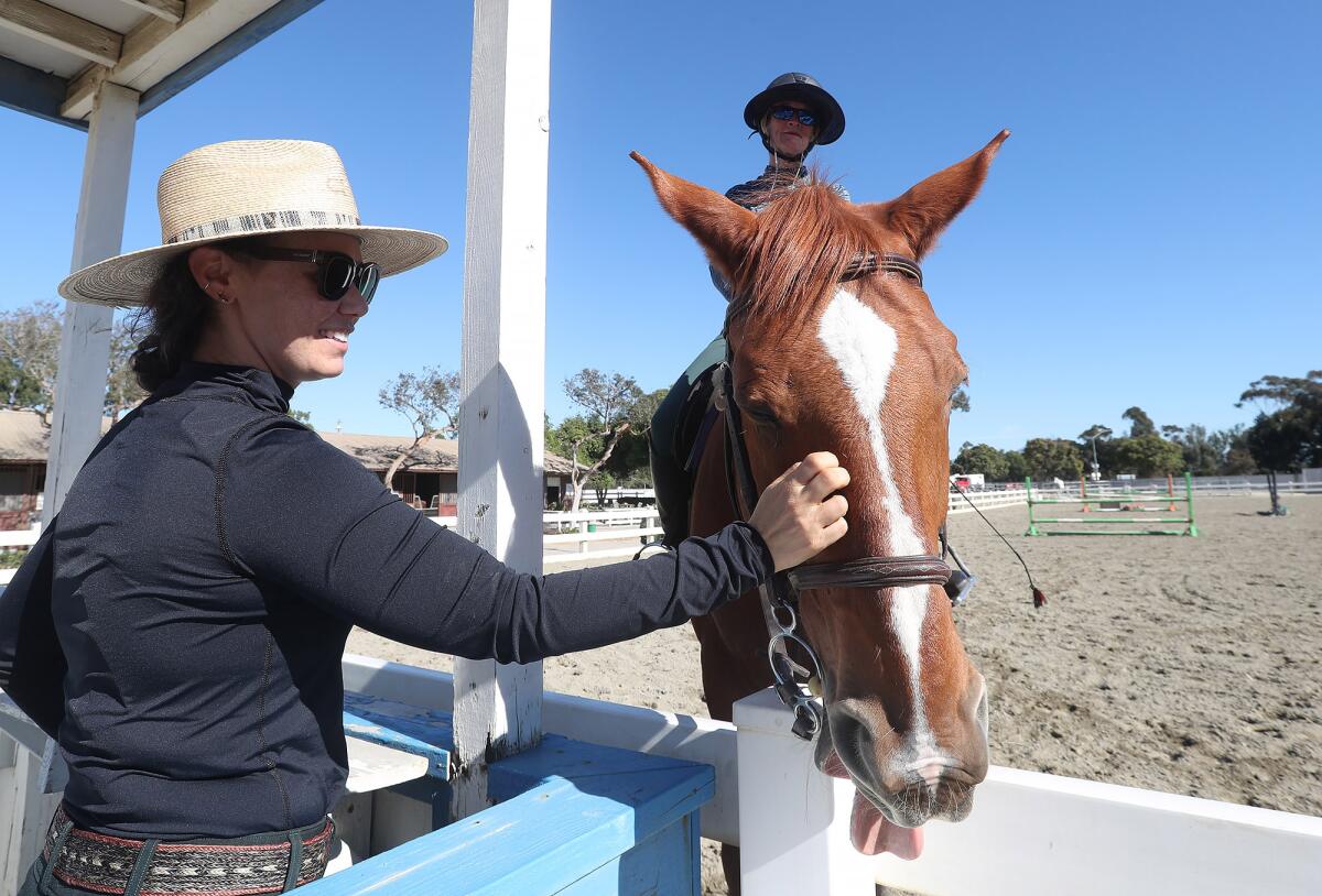 Trainer Sarah Klifa, left, works with Carolyn Beaver, who boards horse Don Juan at the O.C. fairgrounds Equestrian Center. 