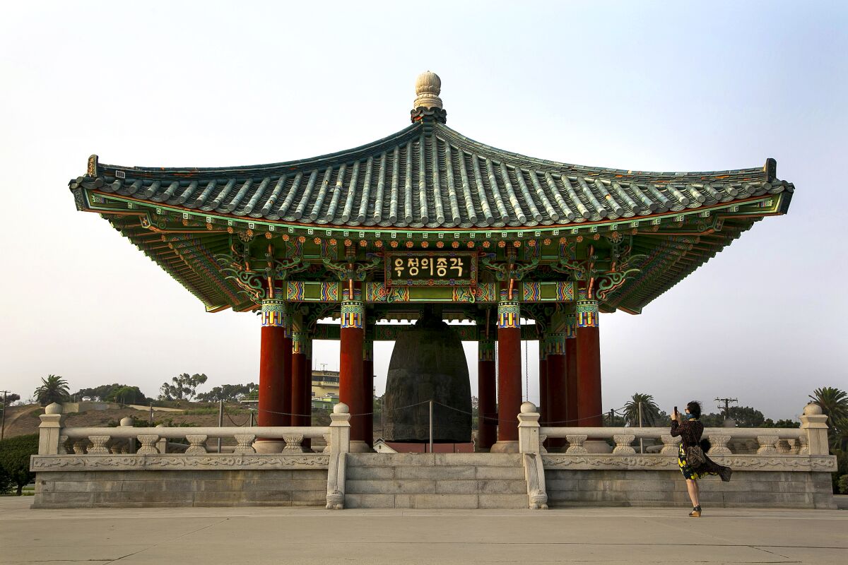 A woman photographs the Korean Friendship Bell at Angels Gate Park.