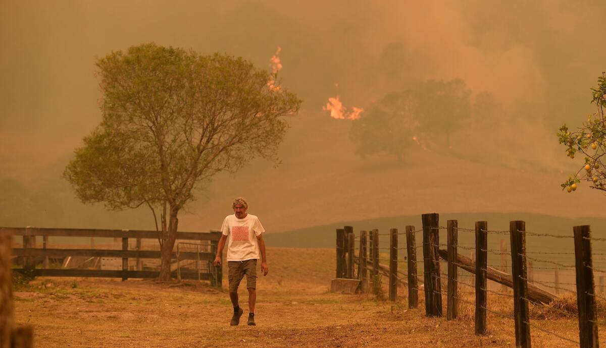 An Australian man walks on a farm Nov. 14 in the New South Wales town of Taree as a bushfire nears.