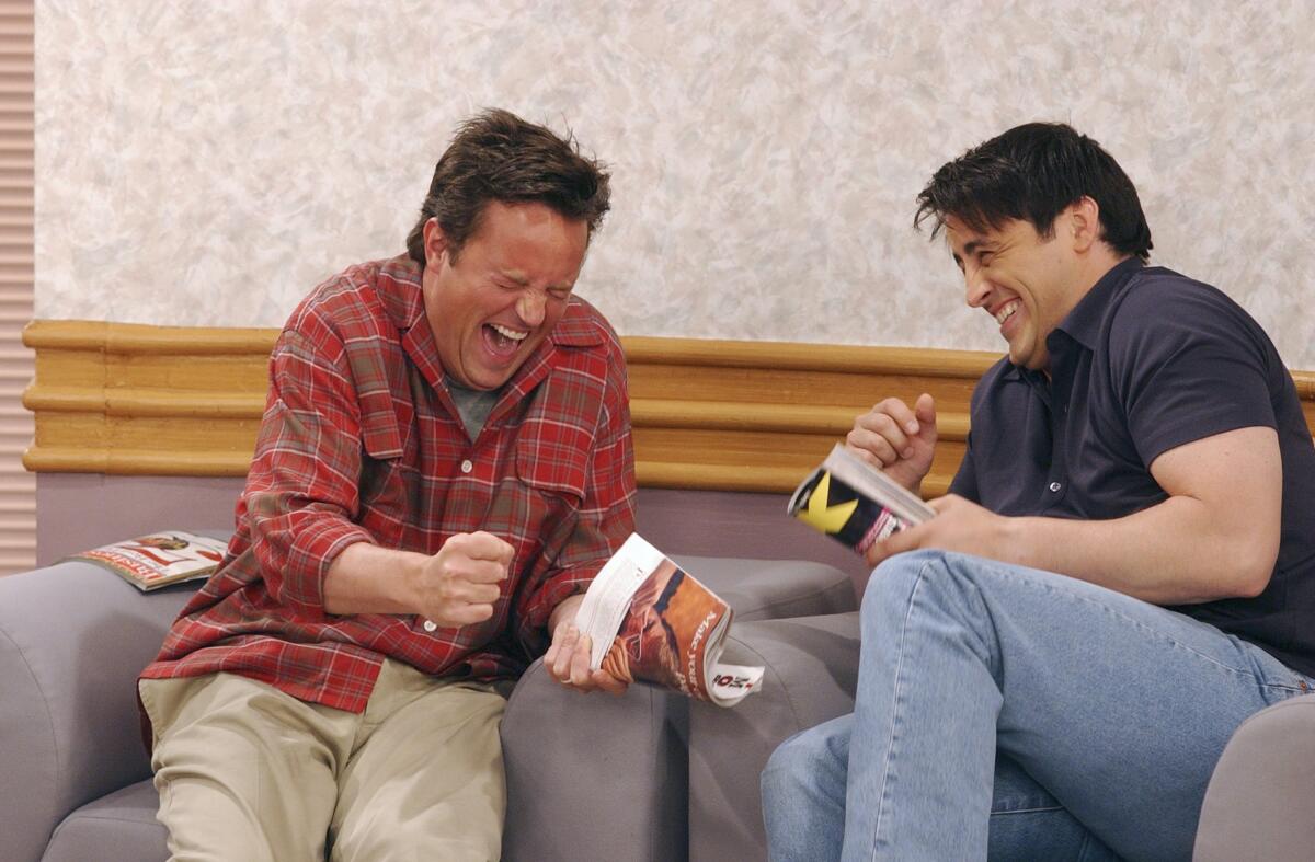 Matthew Perry and Matt LeBlanc sit in flanking armchairs and laugh together