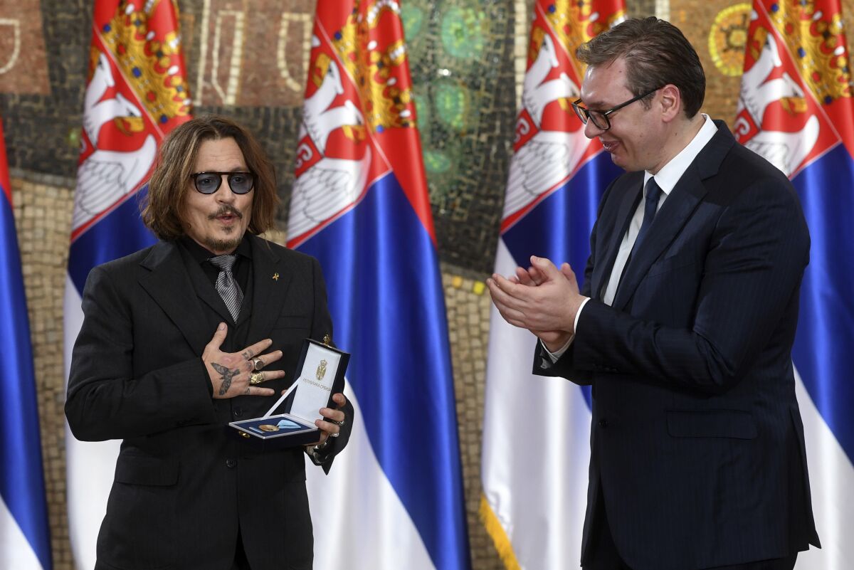 In this photo provided by the Serbian Presidential Press Service, Serbian President Aleksandar Vucic, right, awards the Gold Medal of Merit of the Republic of Serbia to actor Johnny Depp, during a Statehood Day award ceremony in Belgrade, Serbia, Tuesday, Feb. 15, 2022. (Serbian Presidential Press Service via AP)