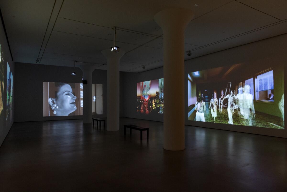 A darkened gallery has floor-to-ceiling images projected along its walls from Pat O'Neill's Ambassador Hotel film.