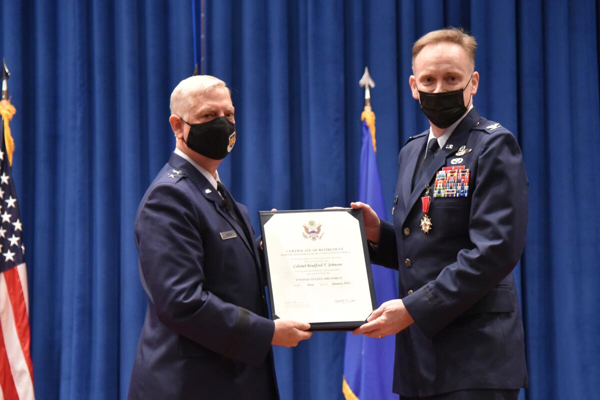 Major Gen. Mark D. Camerer, left, presents Brad Johnson with the official certificate of retirement.