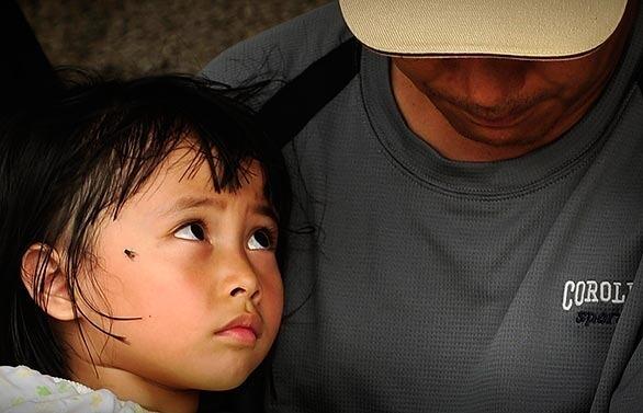An aboriginal girl looks up at her father as they wait for relatives to return at the typhoon rescue center in the town of Chiashien in Kaohsiung county. Many of Typhoon Morakot's victims belong to Taiwan's indigenous tribes, who have lived here for thousands of years before the Han Chinese came in the 17th century -- and whose spiritual attachment to the land runs deep.