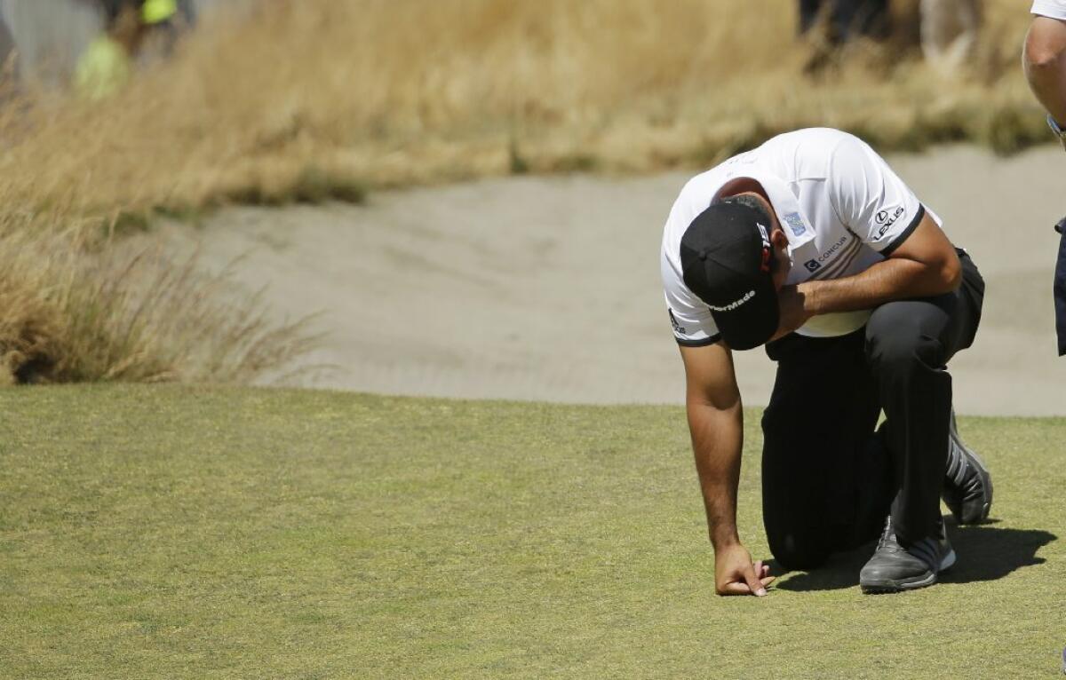 Jason Day kneels while waiting to putt on the ninth hole after collapsing earlier on the fairway during the second round of the 115th U.S. Open at Chambers Bay in University Place, Wash.