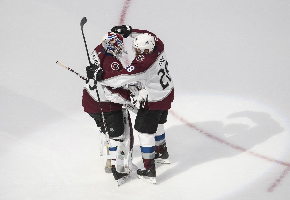 Colorado Avalanche goaltender Michael Hutchinson (35) and teammate Ian Cole (28) celebrate the Avalanche's win over the Dallas Stars in Game 6 of an NHL hockey second-round playoff series, Wednesday, Sept. 2, 2020, in Edmonton, Alberta. (Jason Franson/The Canadian Press via AP)