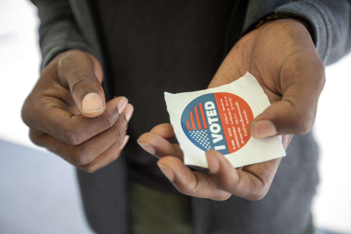 A man holds an "I voted" sticker 