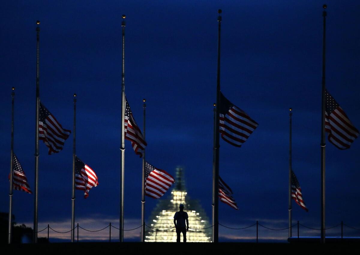 A man walks past a row of American flags that have been lowered to half staff on the Washington Monument grounds near the U.S. Capitol to mark the 14th anniversary of the Sept. 11, 2001, attacks when terrorists hijacked airliners and flew them into the World Trade Center and the Pentagon.