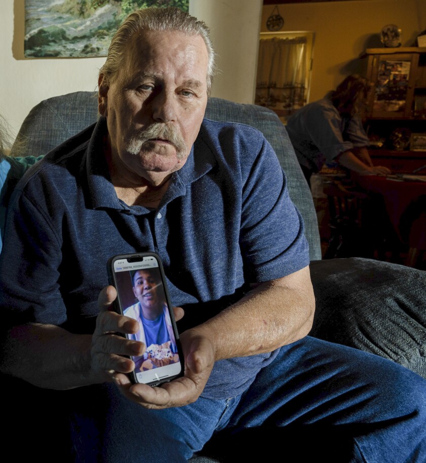 Ray Michalik, Neven Butler's grandfather, with a photograph of Neven on a phone.