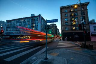 Los Angeles, CA - April 06: (Editor's note: For Liam's story.) In the evening a bus travels between the Baltimore Hotel left, and the King Edward Hotel, right, located at 5th St. and Los Angeles St. on Thursday, April 6, 2023, in Los Angeles, CA. Both hotels are owned by the AIDS Healthcare Foundation and have been converted to single-room occupancy housing for homeless people. (Francine Orr / Los Angeles Times)