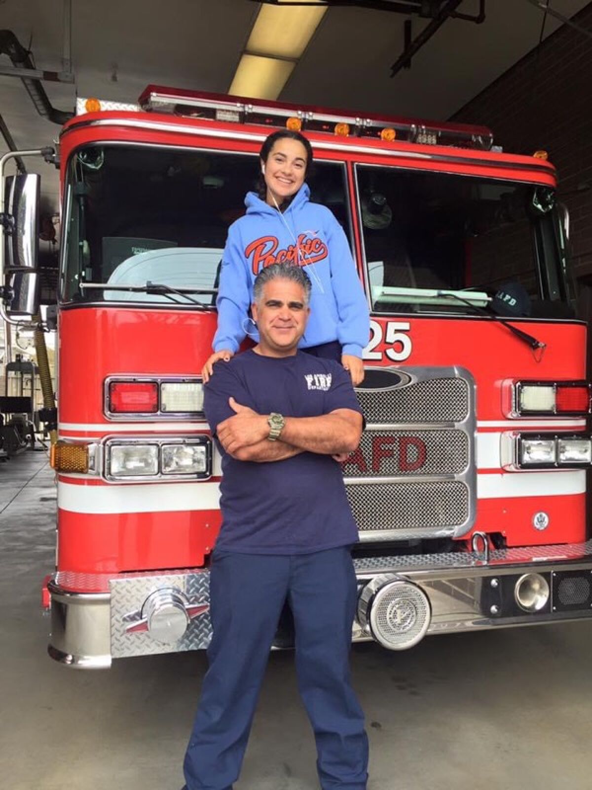 Firefighter Francisco Aguilar and daughter Bella stand in front of a fire truck.