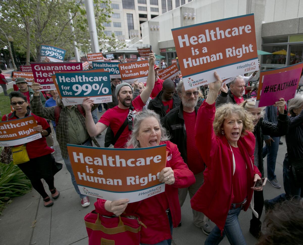 Demonstrators march carrying signs, some that read, "Healthcare is a human right"