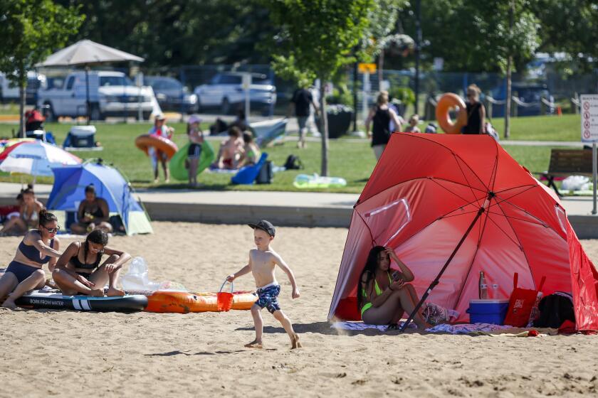 People try to beat the heat at a beach in Chestermere, Alta., Tuesday, June 29, 2021. Environment Canada warns the torrid heat wave that has settled over much of Western Canada won't lift for days. (Jeff McIntosh/The Canadian Press via AP)