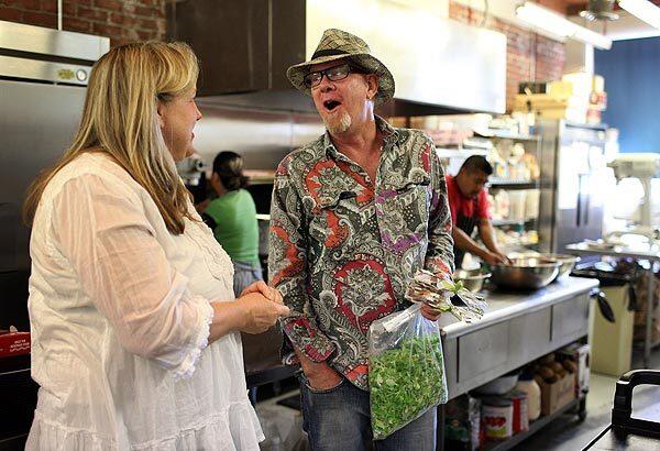 Cam Slocum, right, talks with Christine Moore, owner of Little Flower Candy Company Cafe, after dropping off an order of mache grown on his backyard farm. The cafe is a regular customer of Slocum's.