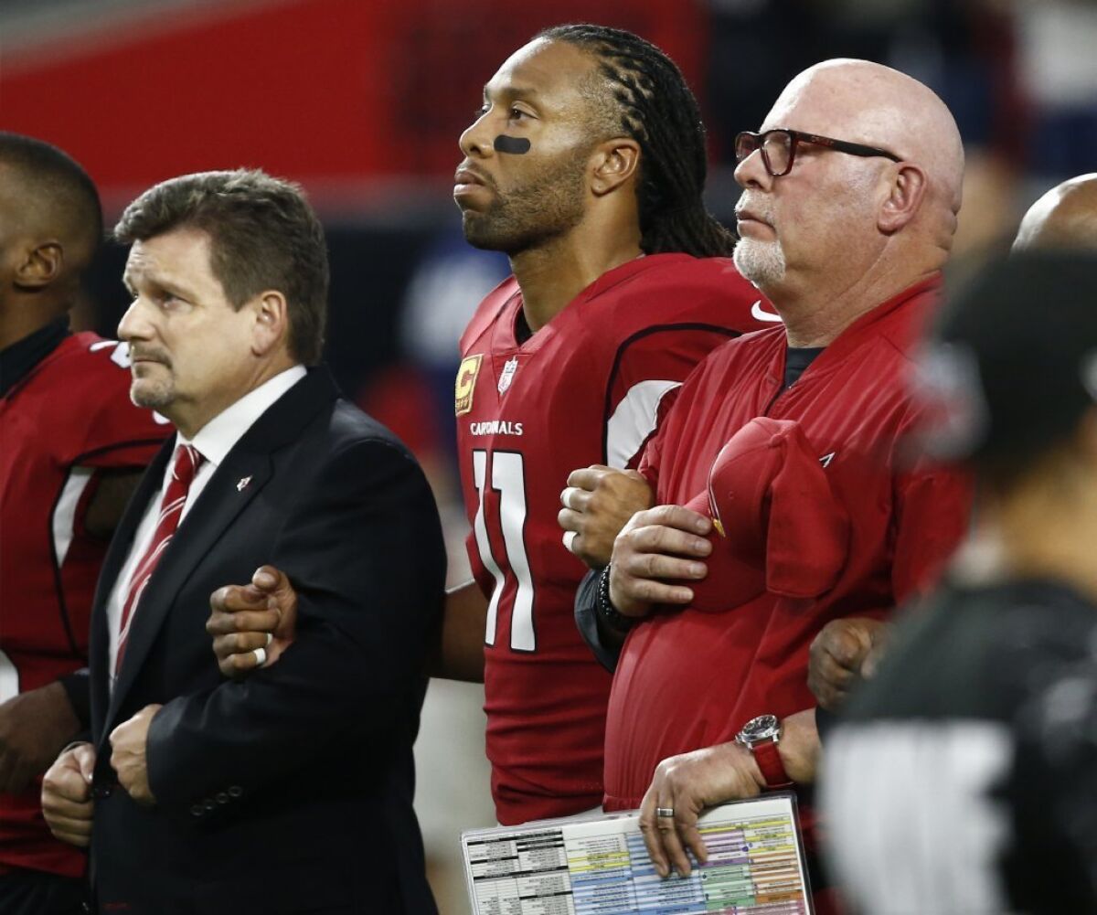 Arizona Cardinals receiver Larry Fitzgerald locks arms with team president Michael Bidwill and coach Bruce Arians before a Monday Night Football game against the Dallas Cowboys.