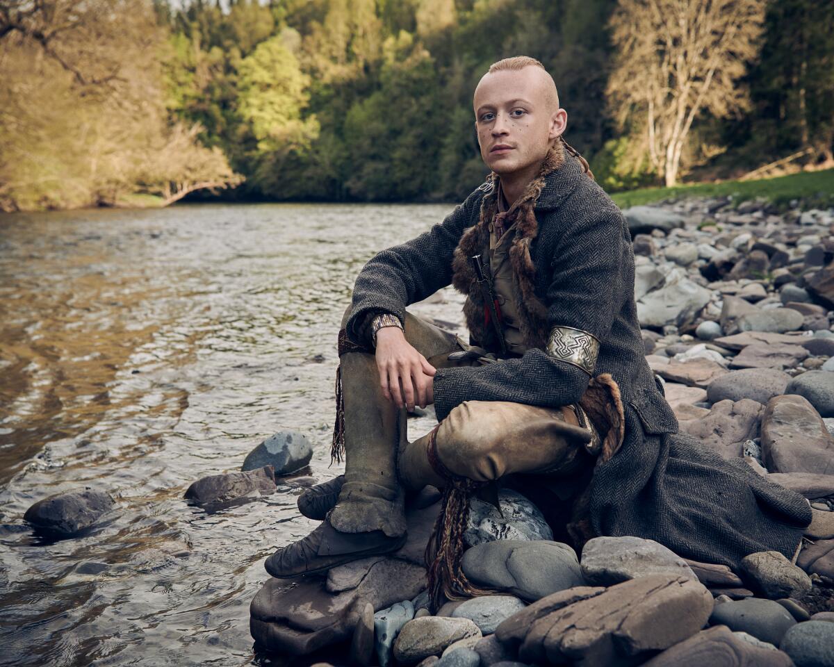 A man sits on stones in a river.