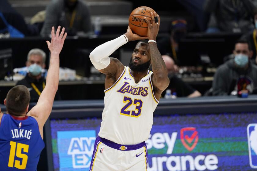 Los Angeles Lakers forward LeBron James, right, shoots over Denver Nuggets center Nikola Jokic during the second half of an NBA basketball game Sunday, Feb. 14, 2021, in Denver. (AP Photo/David Zalubowski)