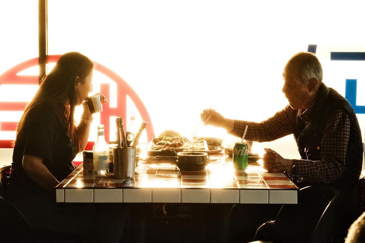 Two customers enjoy a meal, backlit and in shadow, at K-Team BBQ in Koreatown.