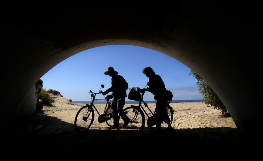 A couple walk their bikes to the beach at Crystal Cove State Park