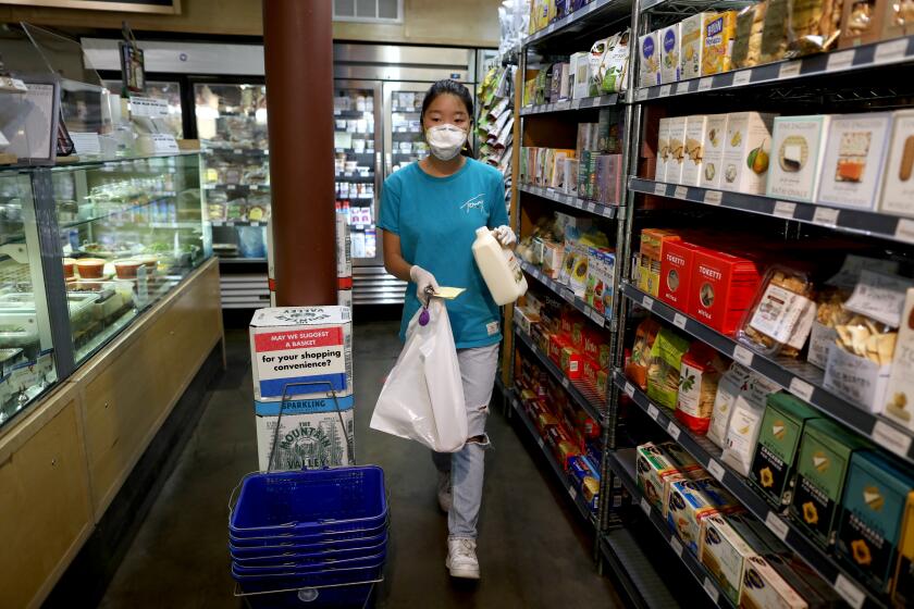LOS ANGELES, CA -- MAY 13: Mira Kwon, 16, a junior at Marlborough School, who is active at the local level with Zoomers to Boomers, shops for a client at Monsieur Marcel Gourmet Market at the Original Farmers Market on Wednesday, May 13, 2020, in Los Angeles, CA. Zoomers to Boomers delivers groceries (NO DELIVERY FEE) to our elderly and immunocompromised community members so they can shelter in place due to the coronavirus. (Gary Coronado / Los Angeles Times)