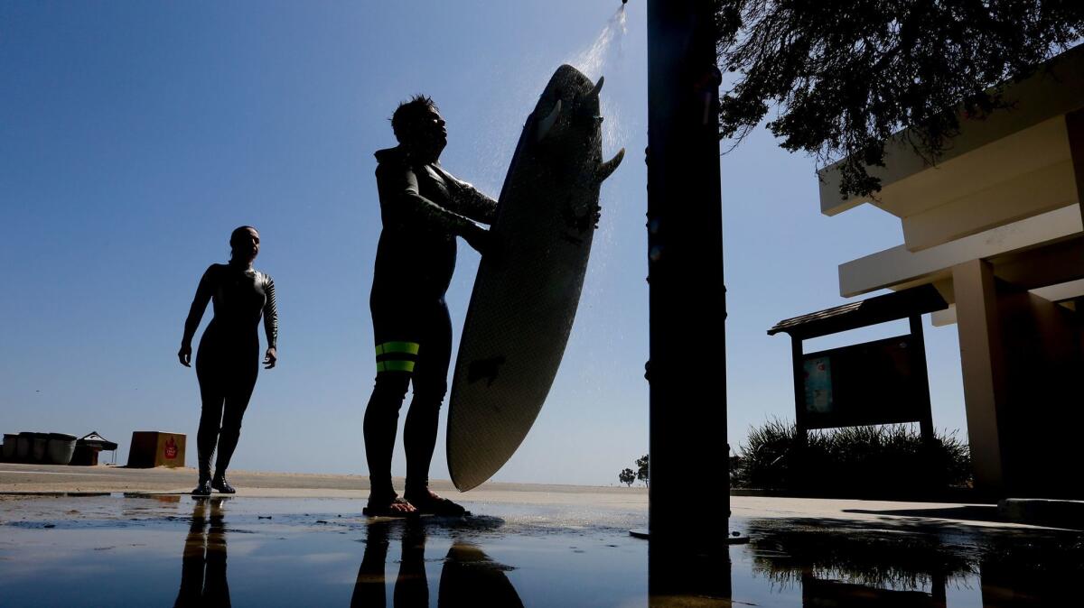 Chris and Petri Carson rinse off after a day of surfing Thursday at Doheny State Beach.