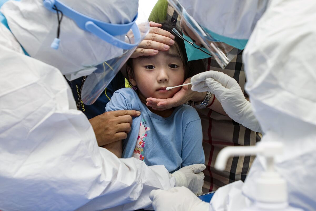 A child reacts to a throat swab during mass testing for COVID-19 in Wuhan in central China's Hubei province Tuesday, Aug. 3, 2021. The coronavirus’s delta variant is challenging China’s costly strategy of isolating cities, prompting warnings that Chinese leaders who were confident they could keep the virus out of the country need a less disruptive approach. (Chinatopix via AP)