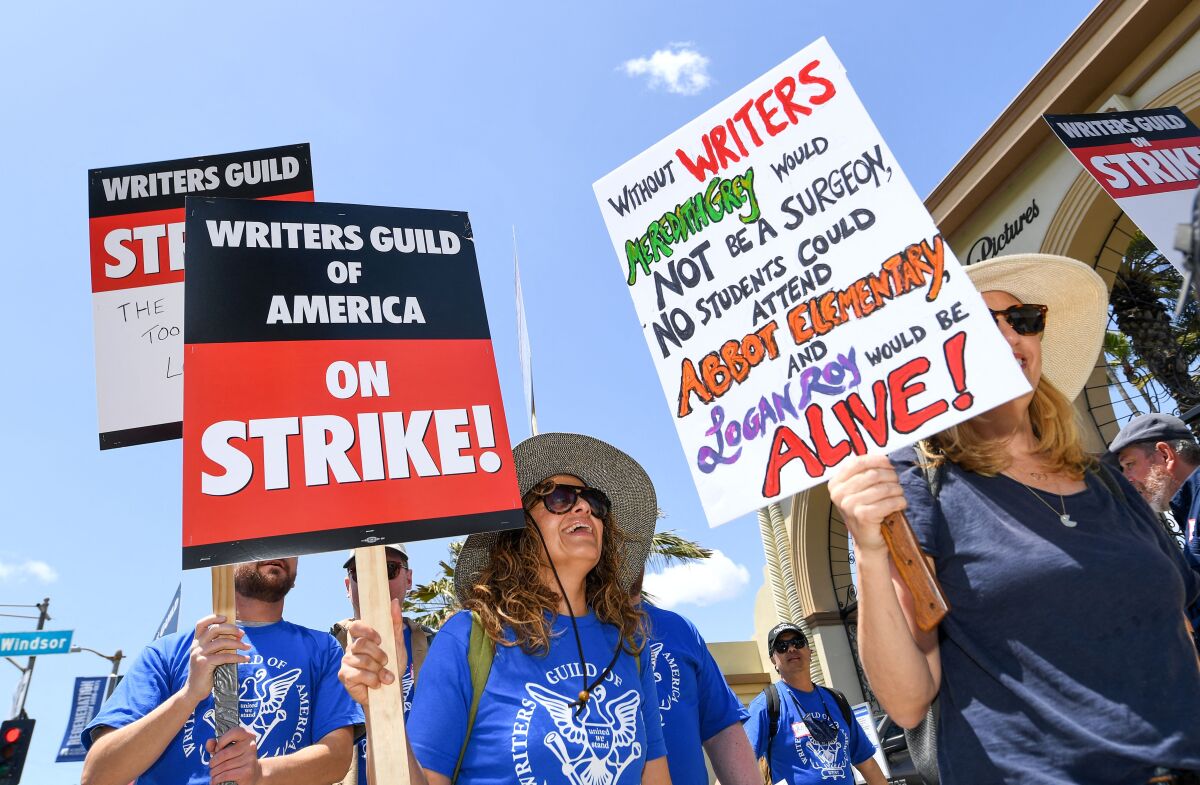 Striking writers wear blue shirts and hold signs.