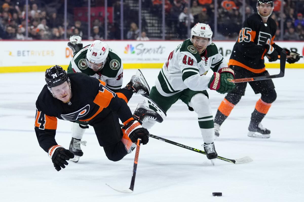 Philadelphia Flyers' Owen Tippett (74) collides with Minnesota Wild's Frederick Gaudreau (89) and Jared Spurgeon (46) during the second period of an NHL hockey game, Thursday, March 23, 2023, in Philadelphia. (AP Photo/Matt Slocum)