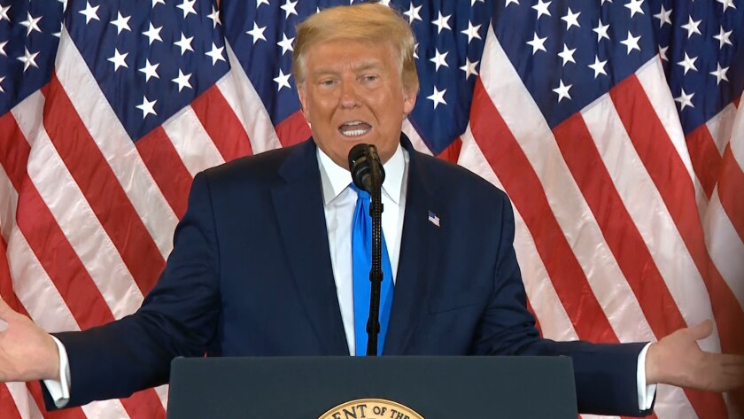 President Trump at a microphone in front of American flags on election day 2020. 