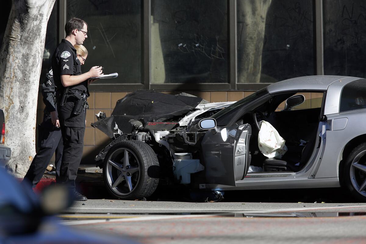 Police investigators the scene where a silver Corvette crashed at the intersection of Olympic Boulevard and Los Angeles Street after a pursuit involving multiple police agencies. The driver of the Corvette was killed by a police officer.