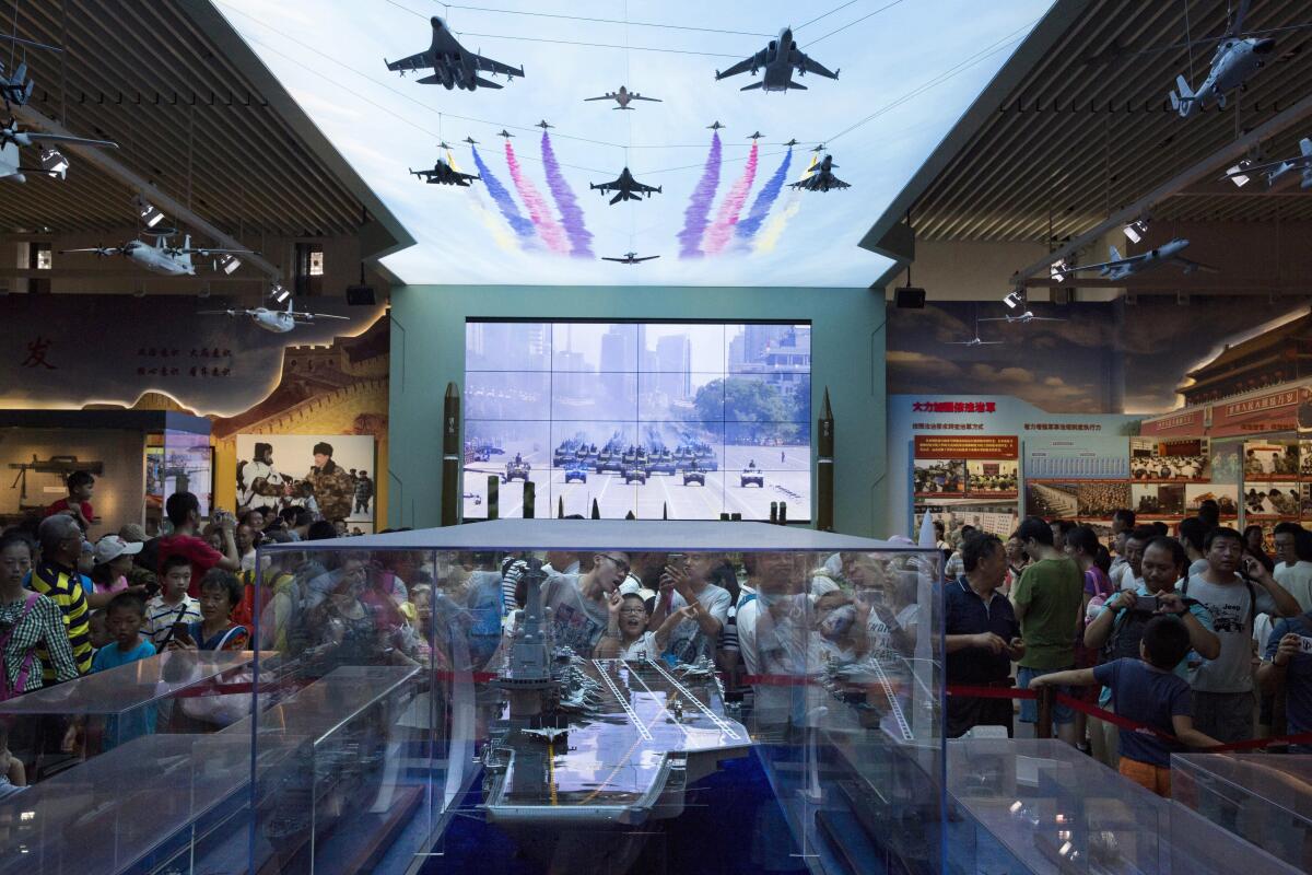 Visitors look at a scale model of a Chinese aircraft carrier