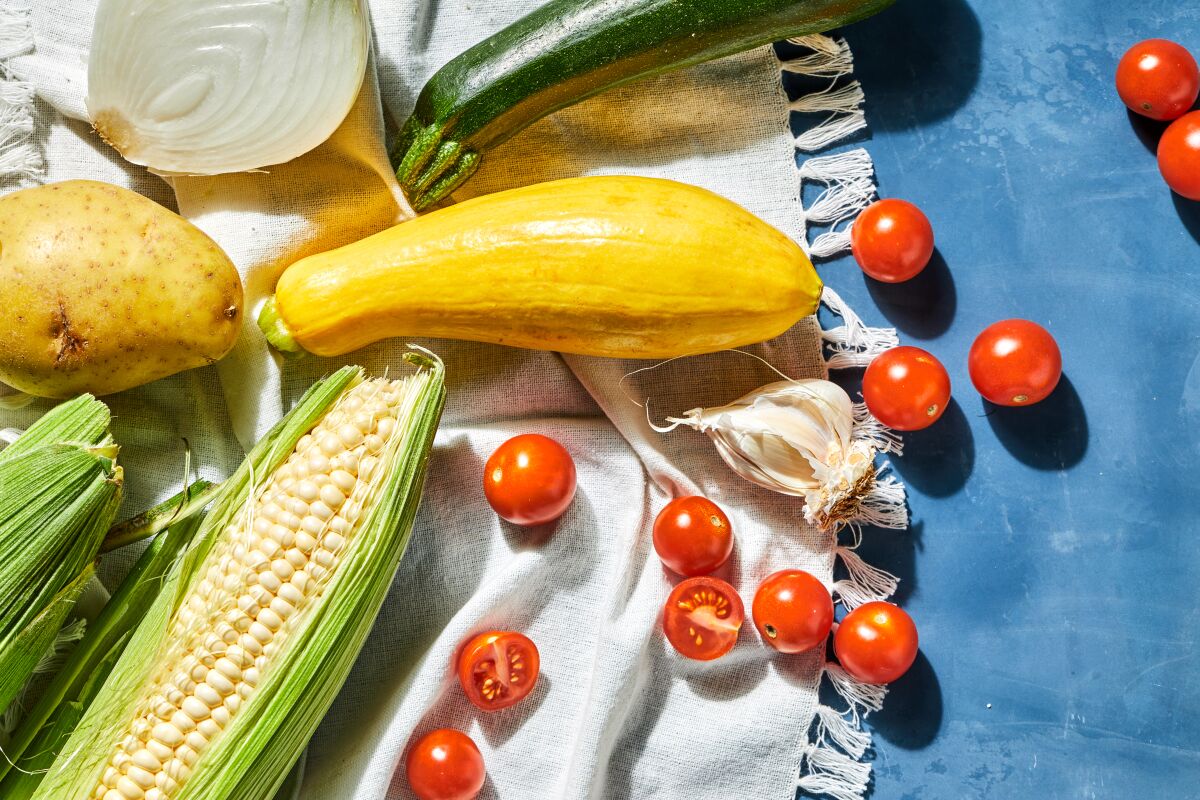 Yellow squash, cherry tomatoes, potato and ears of corn.