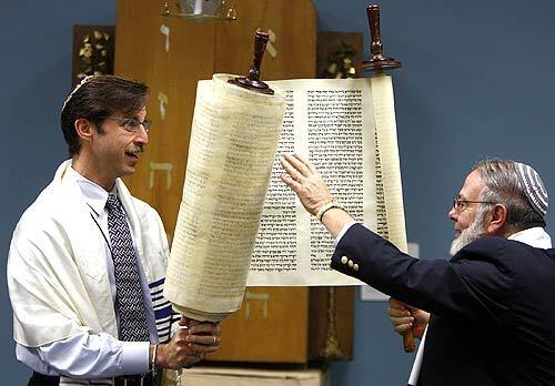 Dr. Joel Kushner, left, and Rabbi Richard N. Levy unroll the Yanov Torah during a ceremony at the Hebrew Union College-Jewish Institute of Religion near USC. The Torah survived the Holocaust by being cut into pieces, hidden during the war and reassembled afterward.