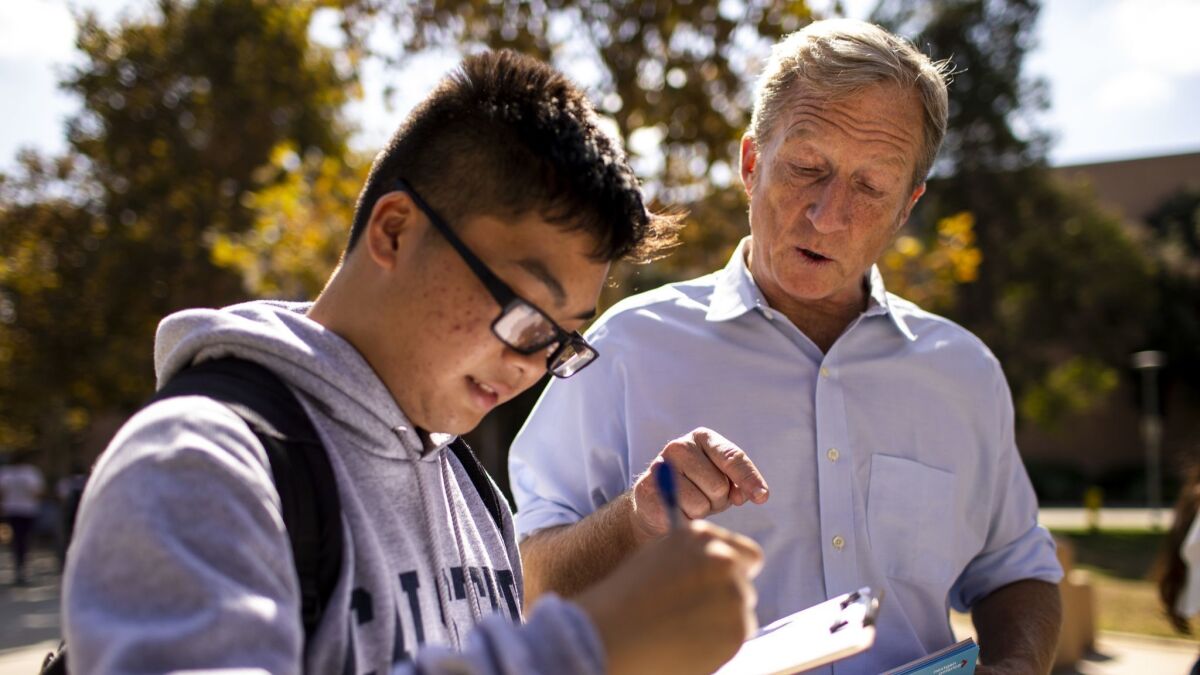 Tom Steyer helps Kevin Huy Nguyen, 18, fill out paperwork to register to vote at Cal State Fullerton. Steyer's advocacy group, NextGen America, is spending $33 million on youth voter outreach this year.