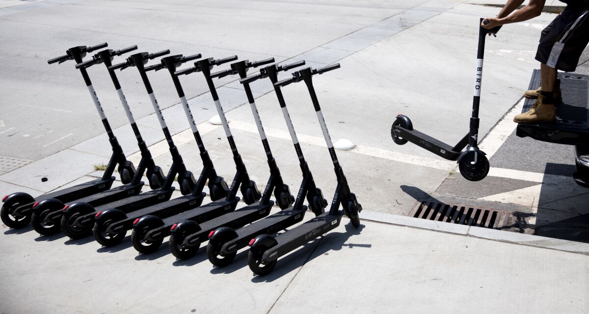 A person lines up electric scooters on a street corner