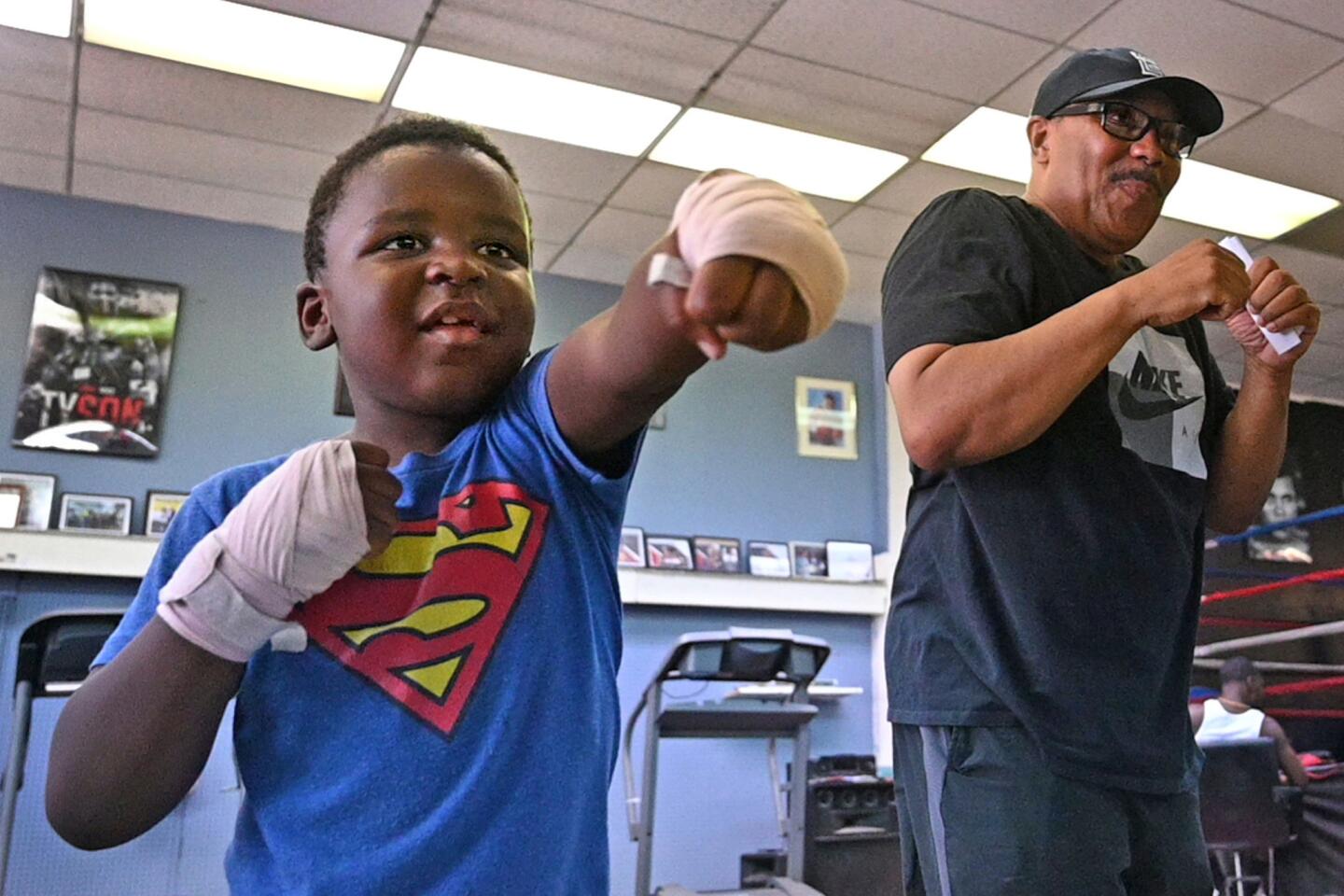 Carter Hopkins, 6, practices his moves facing a mirror, with encouragement from Michael Robinson, co-owner with his wife Germaine Robinson of the Uppercut Boxing Gym. Hopkins is enrolled in a summer camp program at the gym, which relocated to 4408 Park Heights Avenue from Wabash Avenue last August. (all children in camp have permission from parents to be photographed.)