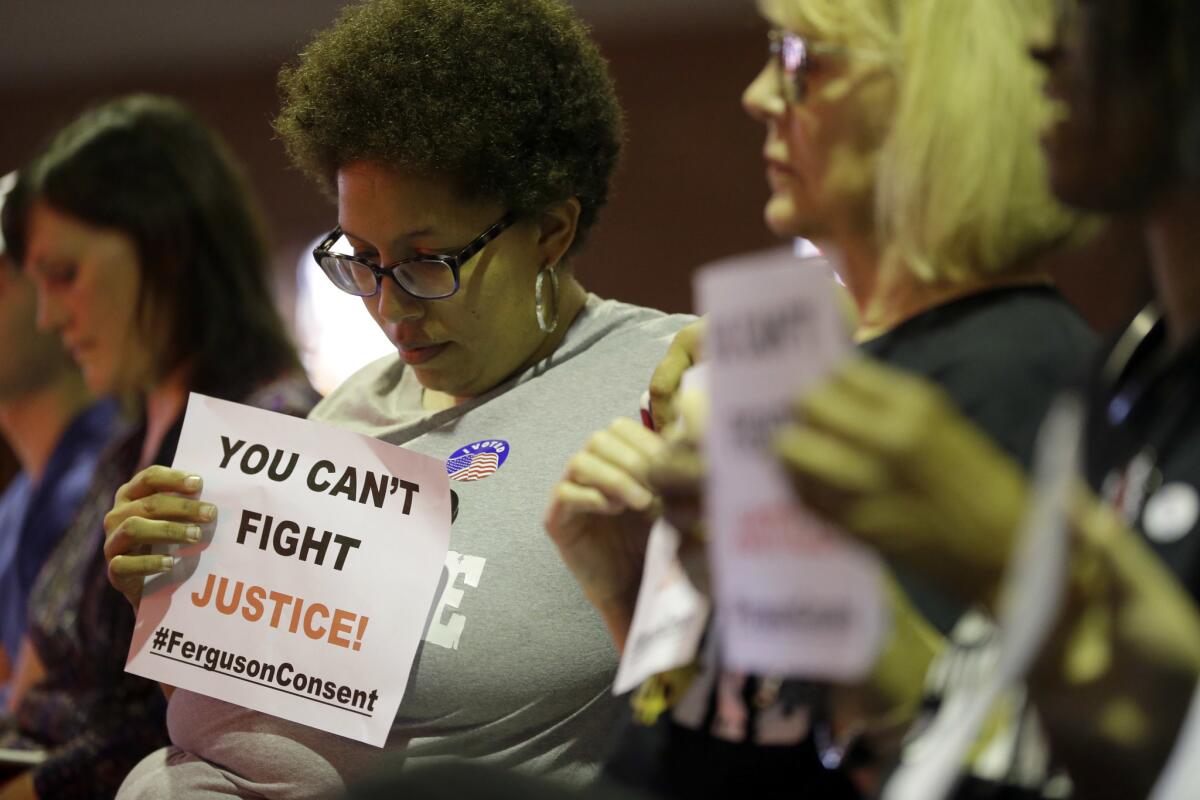 Alicia Street holds a sign during a meeting of the Ferguson City Council on March 15. The council unanimously agreed to accept a U.S. Justice Department plan to overhaul its police force and municipal court system. A judge approved the plan Tuesday.