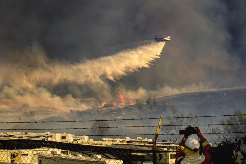 A helicopter makes a water drop on a Santa Ana wind-driven Bond fire
