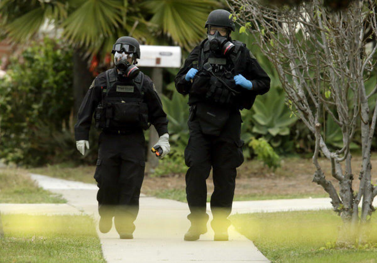 Orange County Sheriff's Department bomb squad members walk away from a home on Bermuda Drive in Costa Mesa where a 52-year-old man apparently committed suicide with an explosive device.