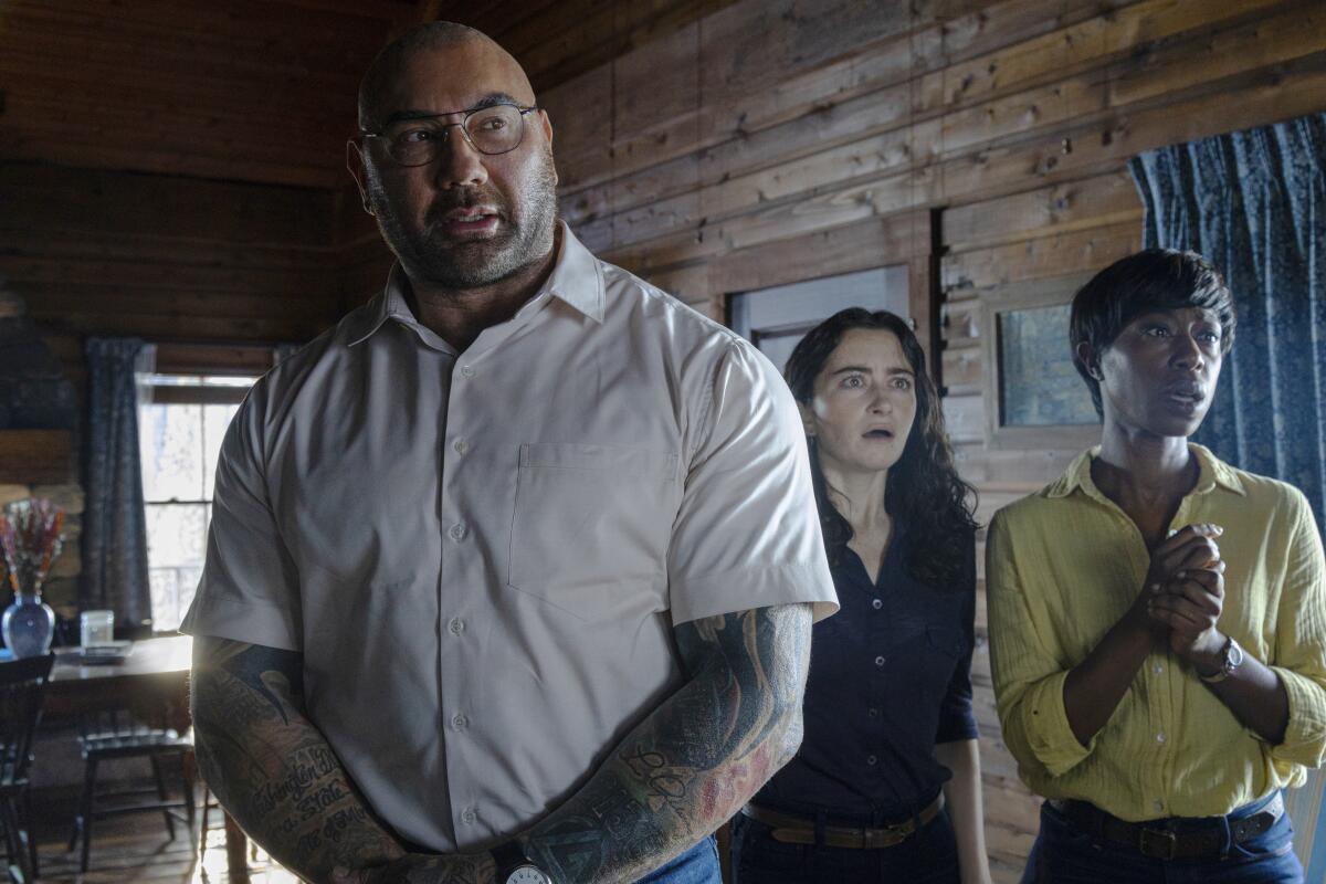 A tattooed man with glasses and two women look distressed in the movie "Knock at the Cabin."