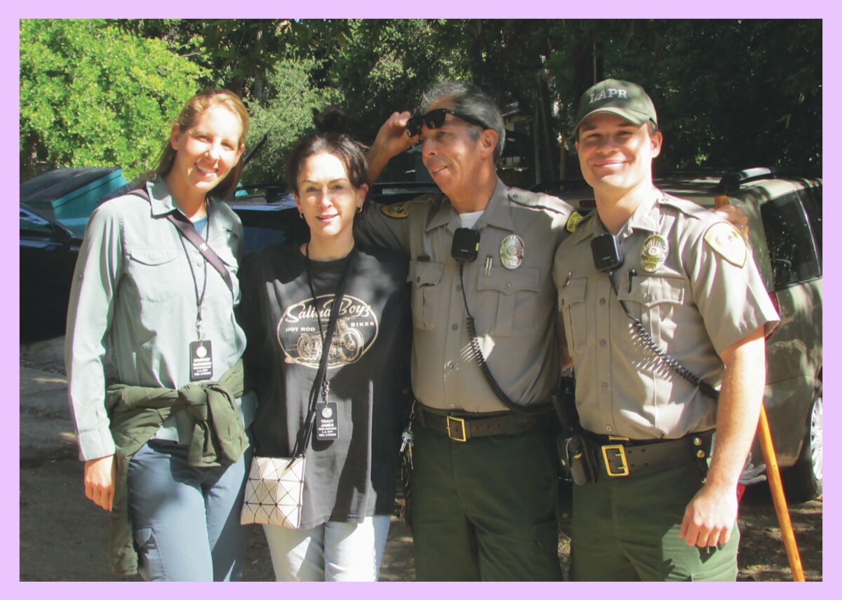 two women wearing lanyards, left, pose with two rangers