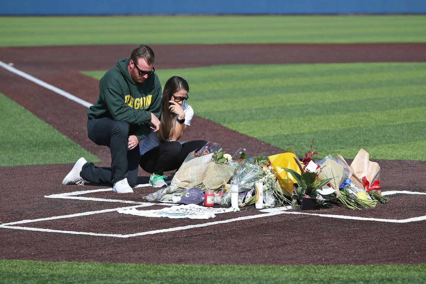 A couple pay their respects at a memorial at home plate in honor of Orange Coast College head baseball coach John Altobelli, who perished with wife Keri, and daughter, Alyssa, in Sunday's helicopter crash with Kobe Bryant.