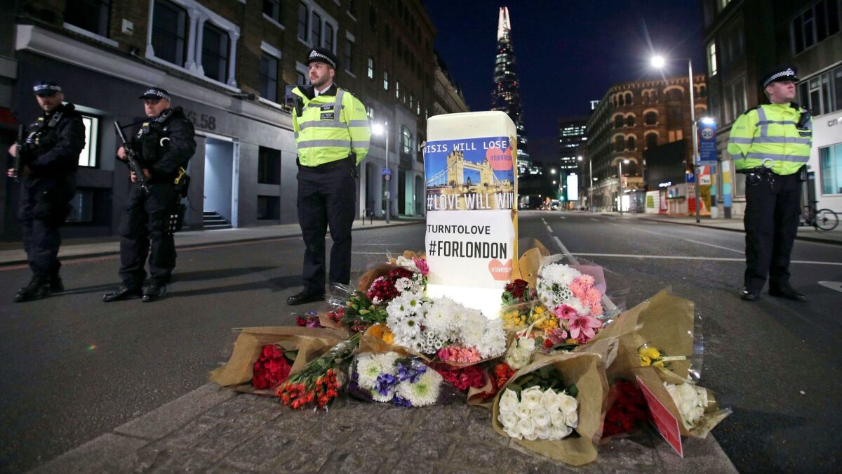British police stand next to floral tributes on Southwark Street in London, near the scene of Saturday's attack.