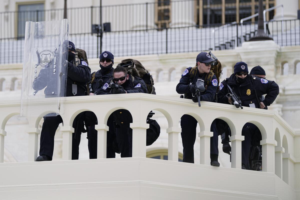 In this Jan. 6, 2021 photo, police keep a watch on demonstrators who tried to break through a barrier at the Capitol. 