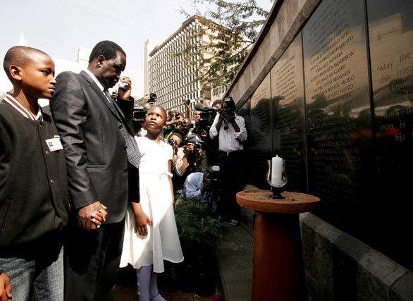 Kenyan Prime Minister Raila Odinga stands with two youths at the memorial for the victims of the U.S Embassy bombing in Nairobi. Kenya and Tanzania are marking the 10th anniversary of deadly bombings at their U.S. embassies, as police conducted a manhunt for the Al Qaeda suspect believed to have masterminded the attacks.