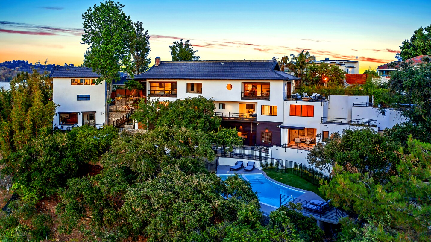 The newly remodeled home in Beachwood Canyon blends elements of Japanese and Traditional styles. Angular wood cabinetry and ribboned stone create visual interest in the chef's kitchen, which has a wide island. The doors and windows of the 6,295-square-foot house are trimmed in mahogany, while the floors are lined with African obeche wood. Mature trees conceal an infinity-edge swimming pool and spa near the edge of the property. The pool overlooks nearby hiking trails.