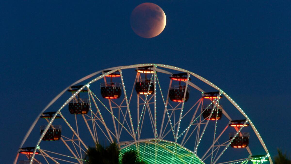 The total lunar eclipse on Sept. 27, 2015, appears behind the ferris wheel at the Irvine Spectrum Center in Irvine,.