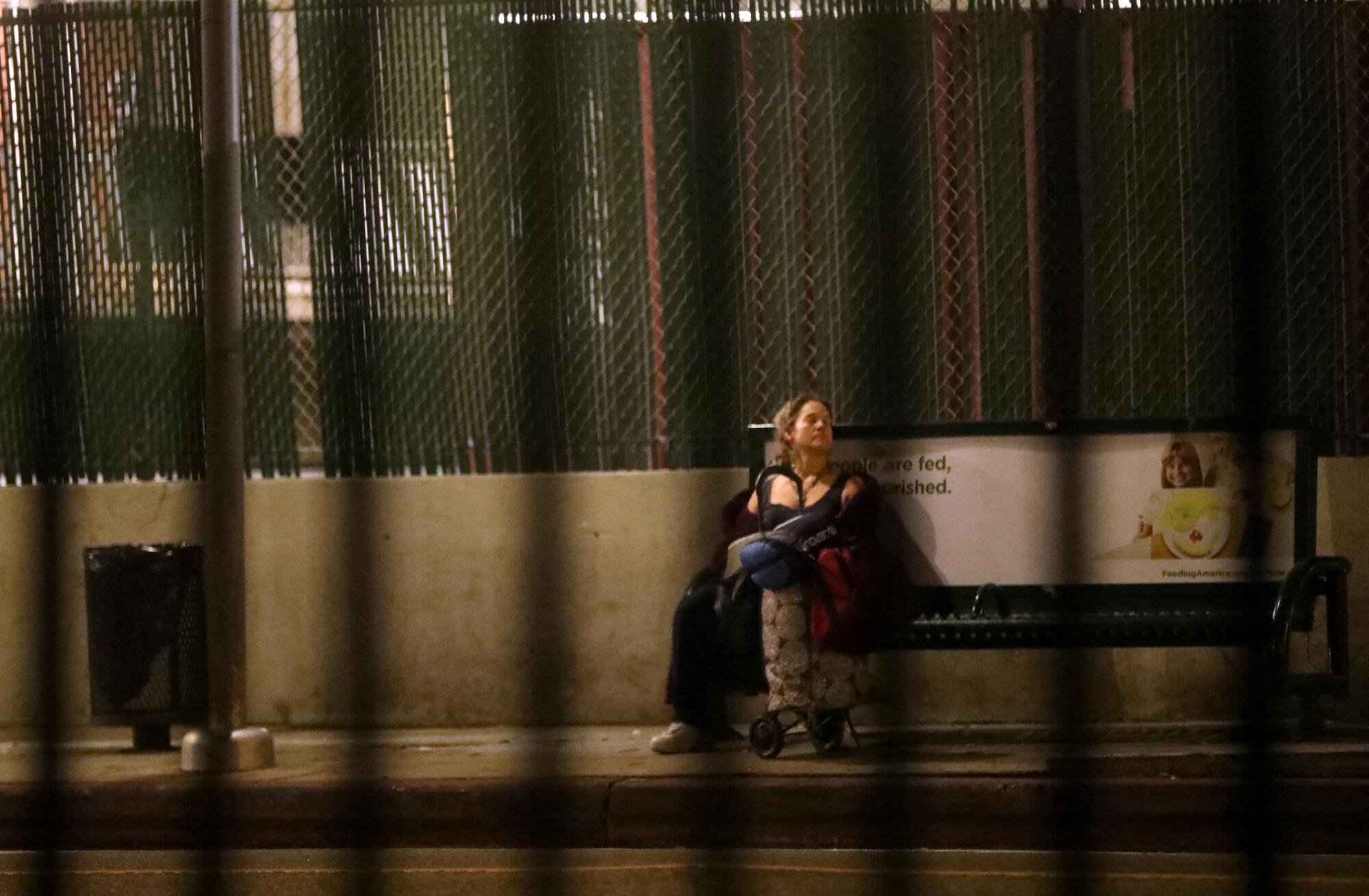 A woman sitting on a bus bench with her belongings in Venice.