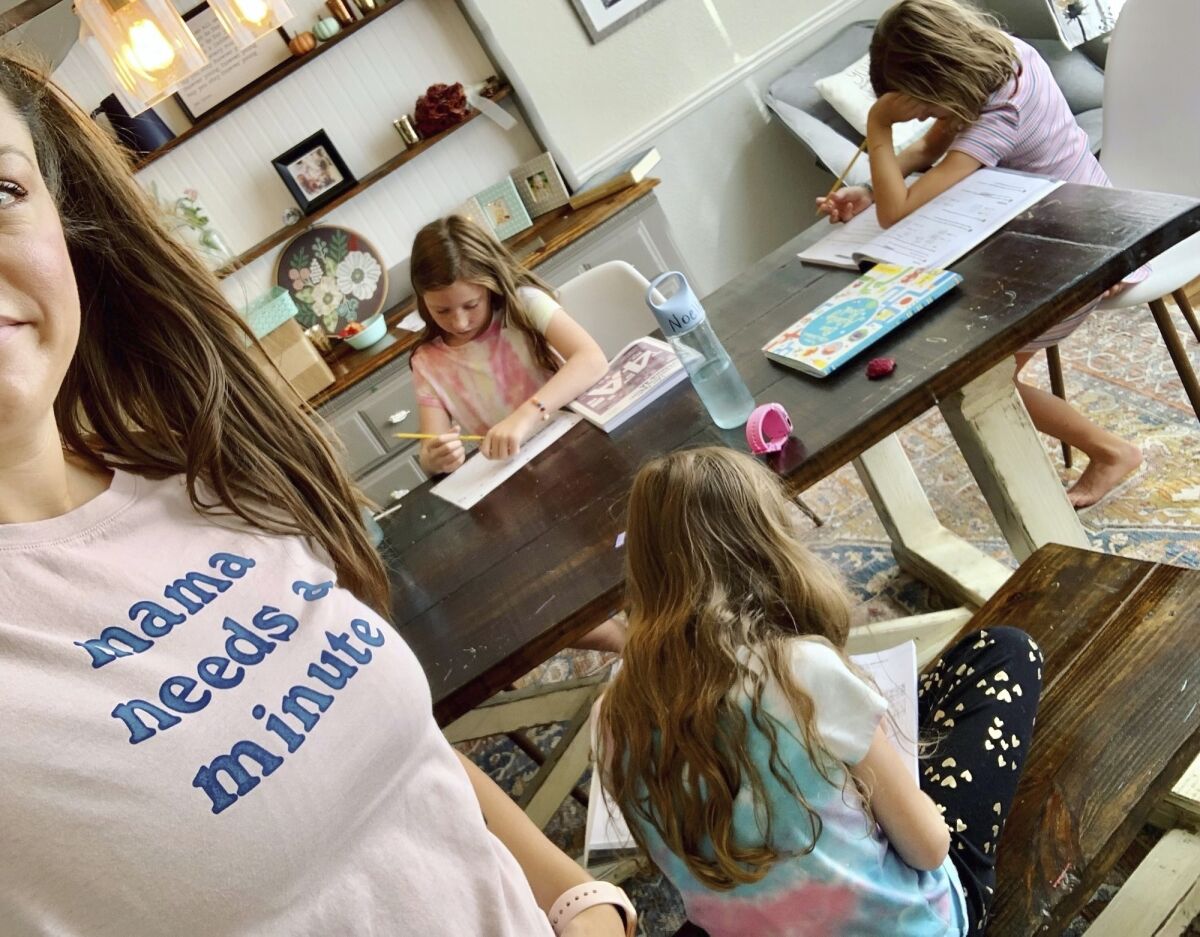 This photo provided by Amber Cessac shows Amber Cessac taking a selfie as her daughters do their homework at their home in Georgetown, Texas on Sept. 9, 2021. A year and a half in, the pandemic is still agonizing families. There is still the exhaustion of worrying about exposure to COVID-19 itself, and the policies at schools and day cares where children spend their time. The spread of the more infectious delta variant, particularly among people who refuse vaccinations, has caused a big increase in infections in children. But there’s also COVID exposures and illnesses — and even minor colds — at schools and day cares that mean children get sent home, forcing parents to scramble for child care. (Amber Cessac via AP)