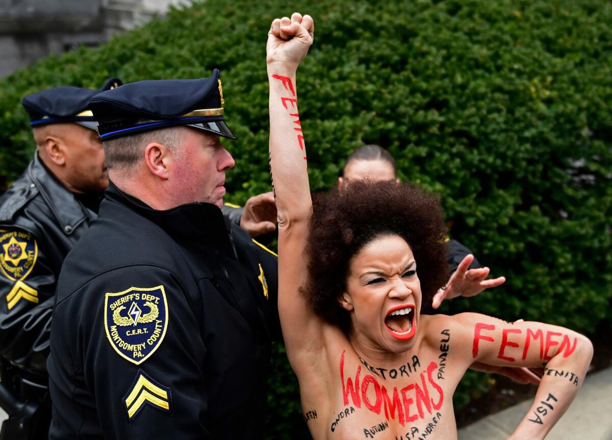 A protester is detained as Bill Cosby arrives for his sexual assault retrial at the Montgomery County Courthouse in Norristown, Pa., on April 9, 2018.